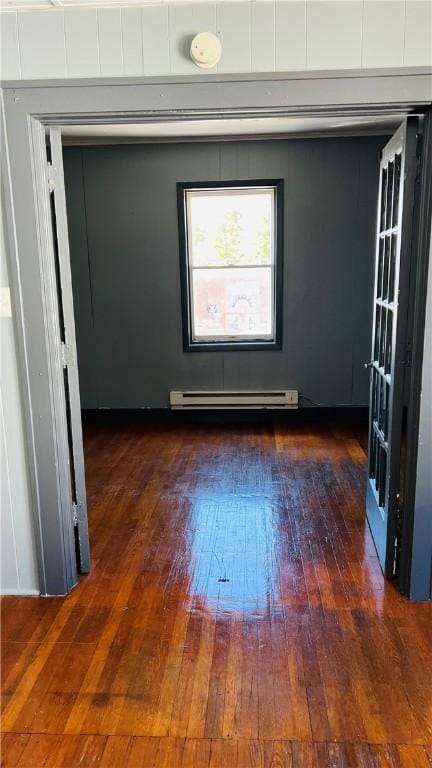 spare room with a baseboard radiator and dark wood-type flooring