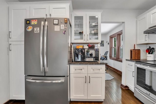 kitchen featuring decorative backsplash, dark stone counters, white cabinetry, stainless steel appliances, and dark hardwood / wood-style flooring