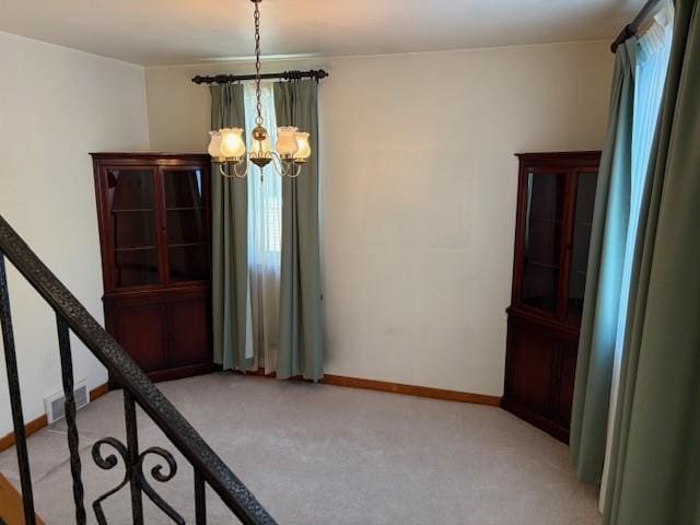 unfurnished dining area with light colored carpet and a chandelier