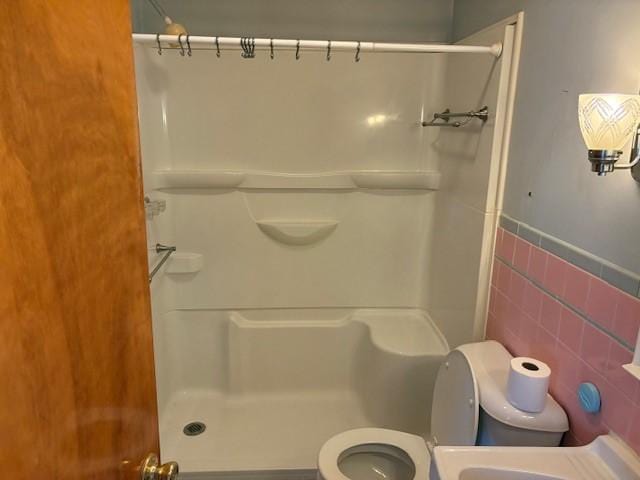 bathroom featuring toilet, tile walls, and walk in shower