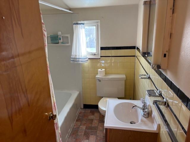 full bathroom with toilet, vanity, tile walls, and shower / bathtub combination