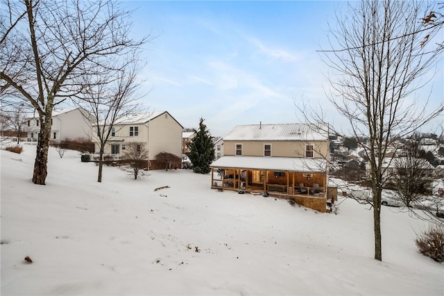 snow covered back of property featuring a porch