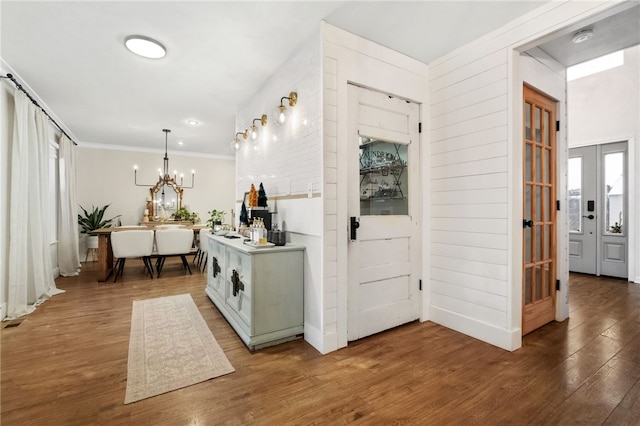 interior space with french doors, a notable chandelier, crown molding, and hardwood / wood-style flooring