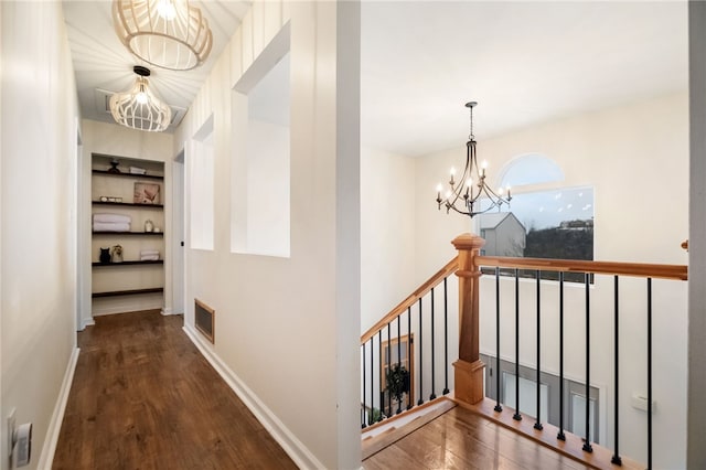 hallway featuring an inviting chandelier, dark hardwood / wood-style floors, and built in shelves