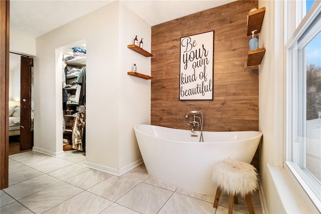 bathroom with tile patterned floors, a bathtub, and wooden walls