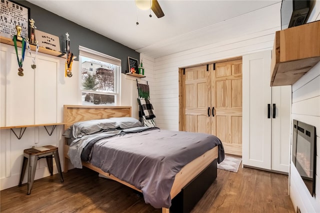 bedroom featuring ceiling fan, hardwood / wood-style flooring, and wood walls