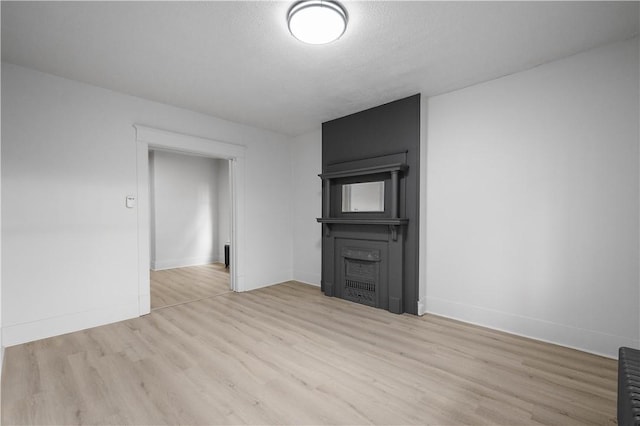 unfurnished living room featuring light wood-type flooring and a textured ceiling