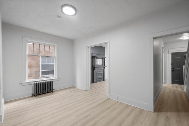 spare room featuring radiator and light wood-type flooring