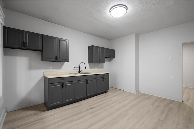 kitchen with sink, a textured ceiling, and light hardwood / wood-style flooring