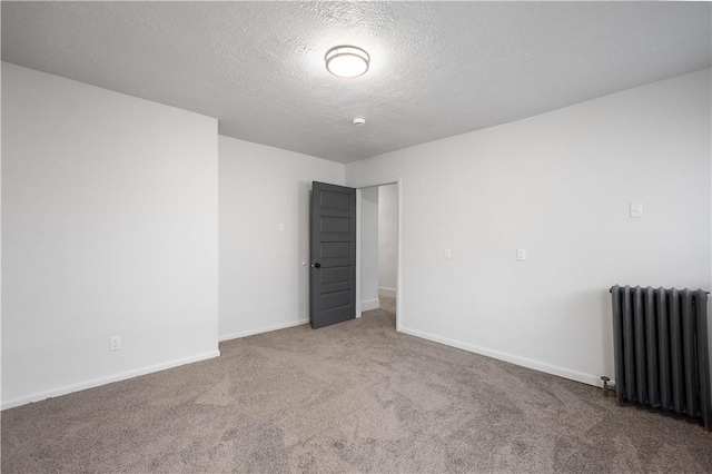 carpeted spare room featuring radiator and a textured ceiling