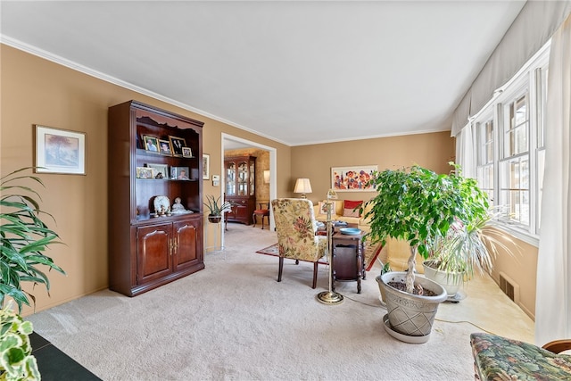 sitting room featuring ornamental molding and light carpet