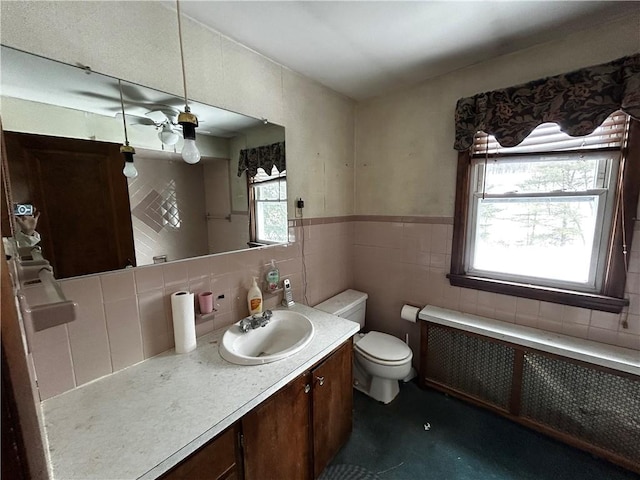 bathroom featuring a wealth of natural light, toilet, radiator heating unit, and vanity