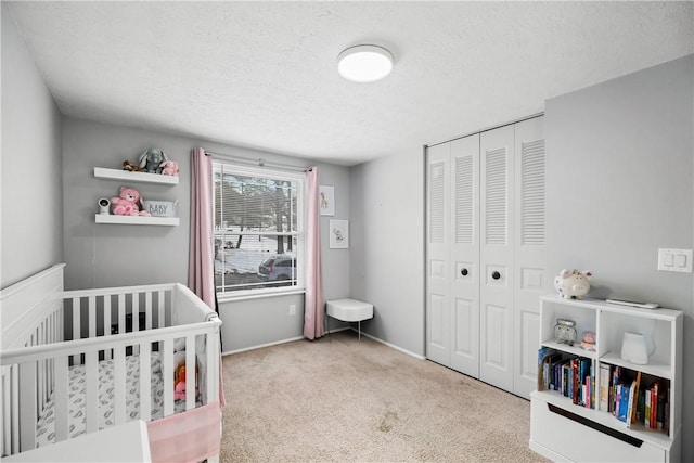 carpeted bedroom featuring a closet, a crib, and a textured ceiling