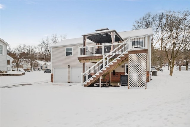 snow covered property with a garage and a wooden deck