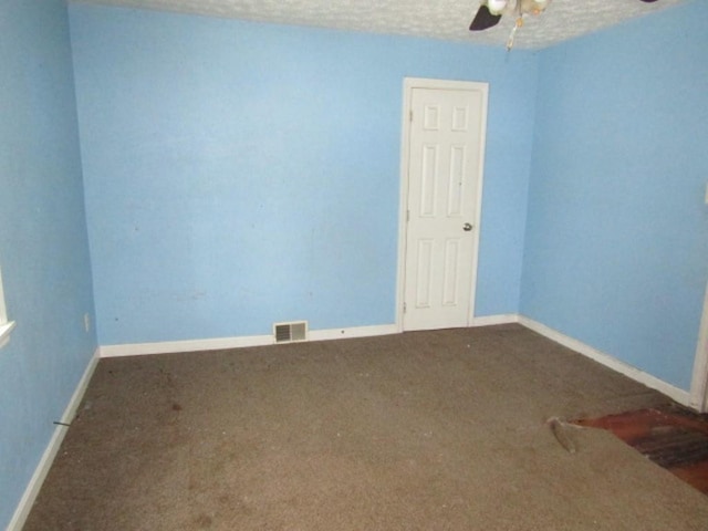 empty room featuring ceiling fan, a textured ceiling, and dark colored carpet