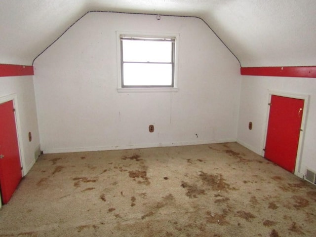 additional living space featuring lofted ceiling and carpet flooring