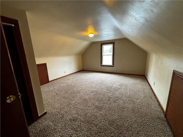 bonus room with lofted ceiling and carpet flooring