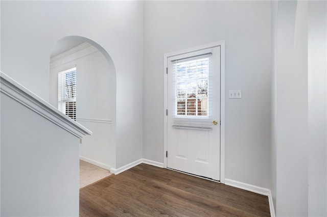 foyer entrance with dark wood-type flooring, ornamental molding, and a wealth of natural light