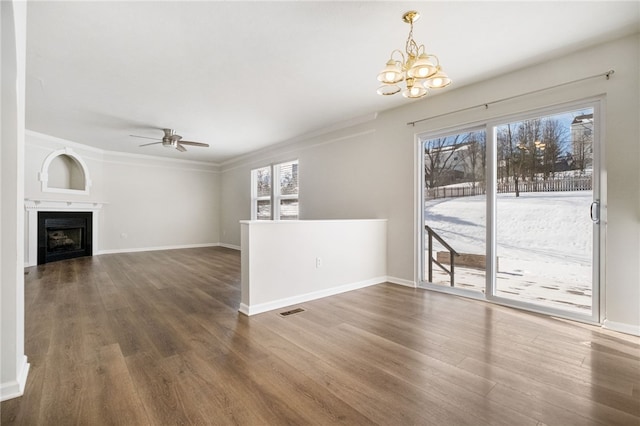 unfurnished living room with a healthy amount of sunlight, dark hardwood / wood-style floors, and ceiling fan with notable chandelier