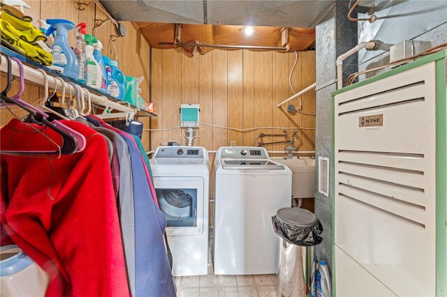 clothes washing area featuring sink, wooden walls, and independent washer and dryer