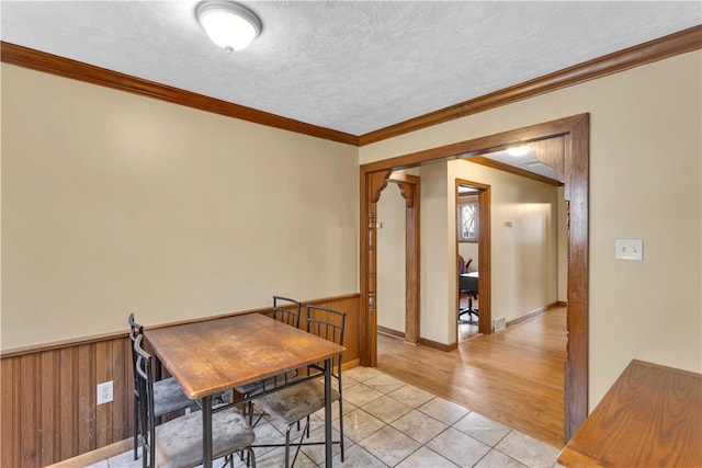 dining area featuring light tile patterned floors, crown molding, and a textured ceiling