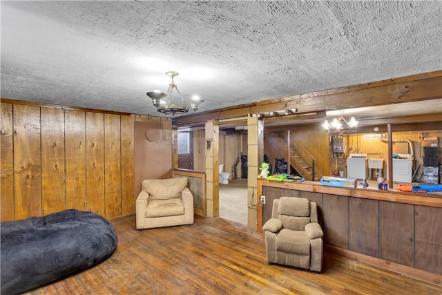 basement with washer / clothes dryer, a chandelier, hardwood / wood-style floors, and wooden walls