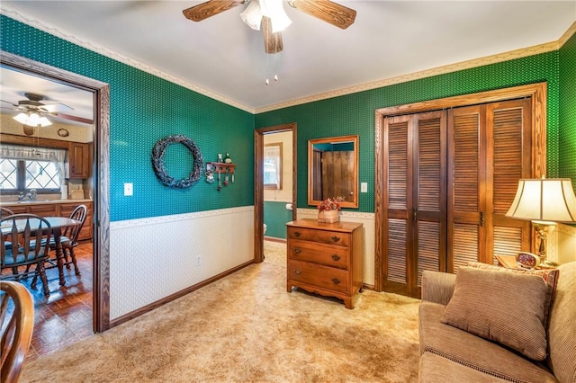 living area featuring ceiling fan, light colored carpet, and ornamental molding