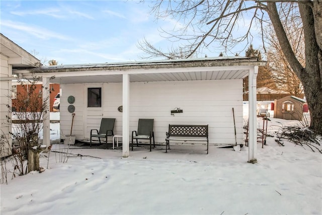 snow covered house featuring a shed