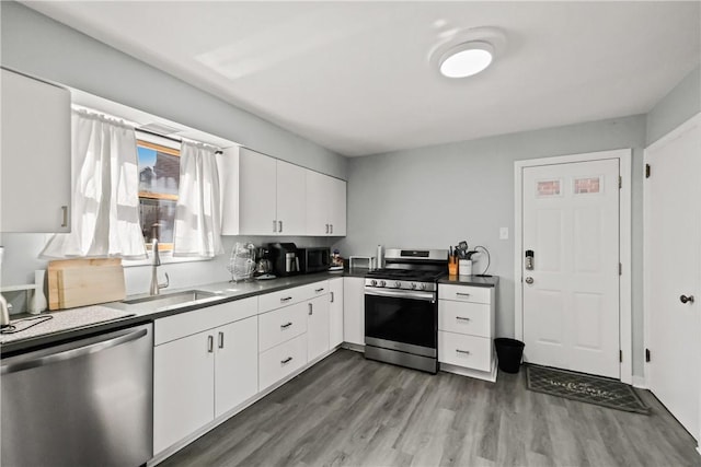 kitchen with dark hardwood / wood-style floors, appliances with stainless steel finishes, white cabinets, and sink