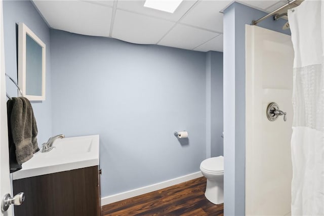 bathroom featuring hardwood / wood-style floors, a shower with curtain, a drop ceiling, vanity, and toilet