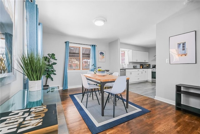 dining area featuring sink and dark wood-type flooring