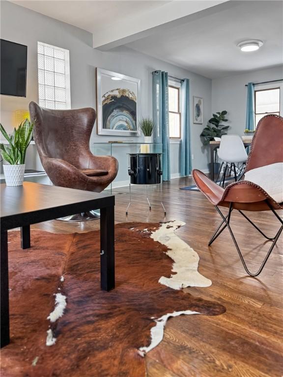 living area featuring beam ceiling and wood-type flooring