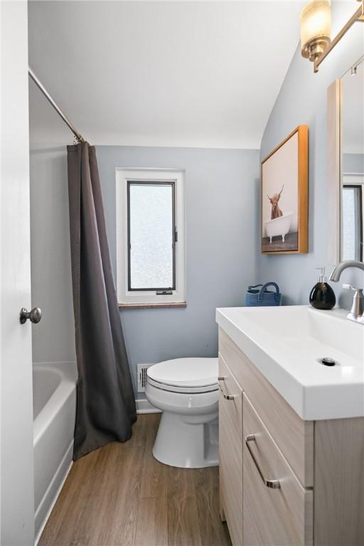 full bathroom with hardwood / wood-style floors, toilet, a wealth of natural light, shower / bath combo, and vanity