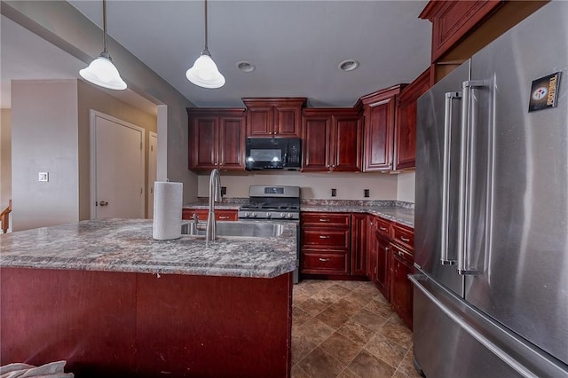 kitchen with appliances with stainless steel finishes, a kitchen island with sink, hanging light fixtures, and sink