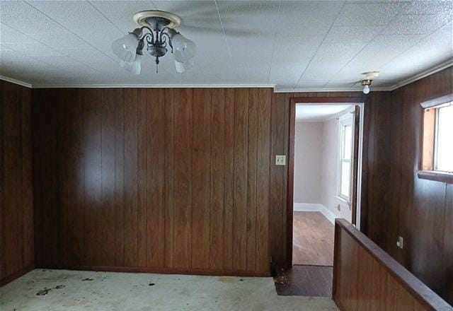 unfurnished room with ceiling fan, crown molding, and wood walls