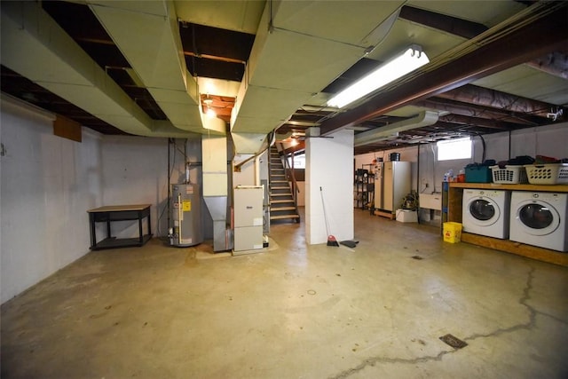 basement with heating unit, refrigerator, washing machine and clothes dryer, and gas water heater