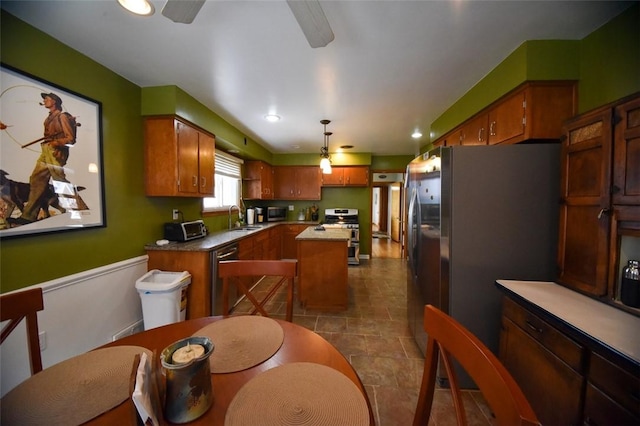 kitchen with ceiling fan, decorative light fixtures, a center island, sink, and appliances with stainless steel finishes