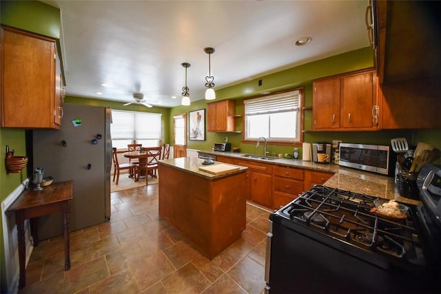 kitchen with a center island, stainless steel appliances, sink, hanging light fixtures, and ceiling fan