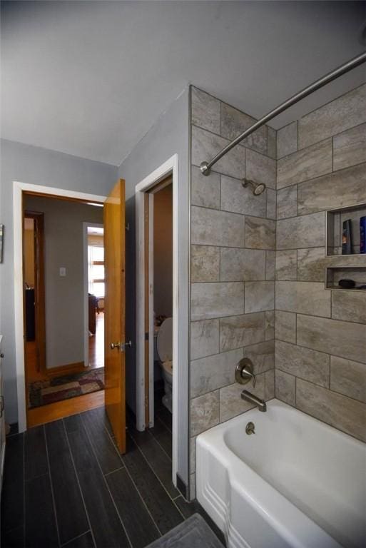 bathroom featuring toilet and tiled shower / bath combo