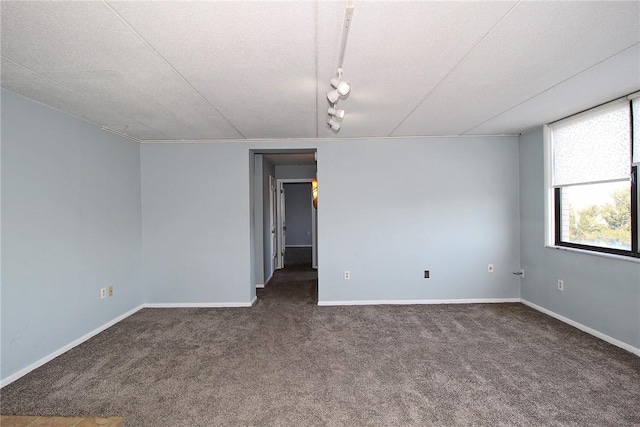 carpeted empty room featuring track lighting