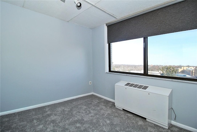 unfurnished room with radiator heating unit and dark carpet