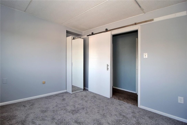 unfurnished bedroom with carpet flooring and a barn door