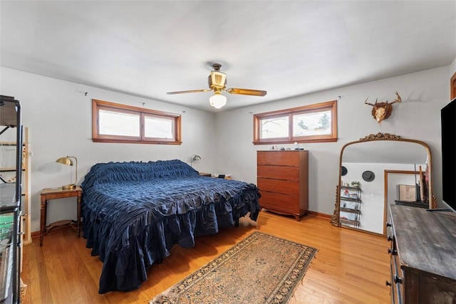 bedroom featuring ceiling fan, multiple windows, and light hardwood / wood-style floors