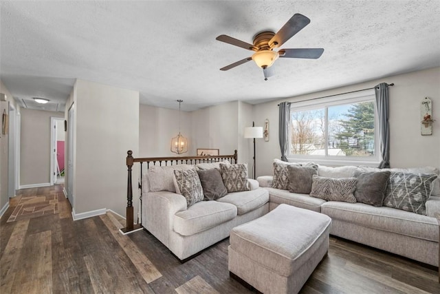 living room with dark hardwood / wood-style flooring, ceiling fan with notable chandelier, and a textured ceiling