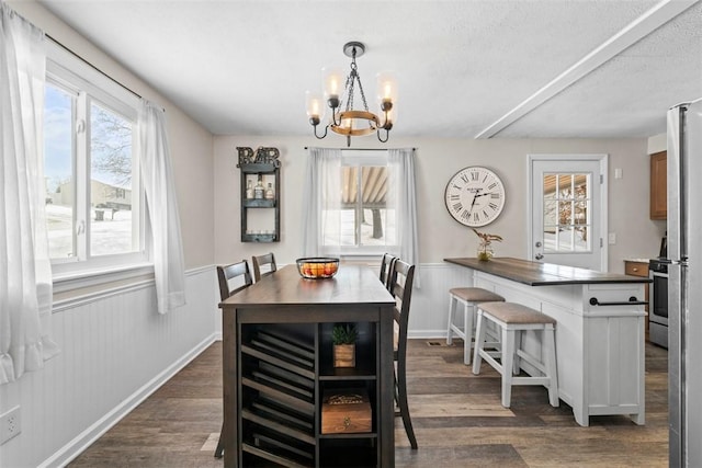 dining area with a textured ceiling, dark hardwood / wood-style flooring, and a notable chandelier