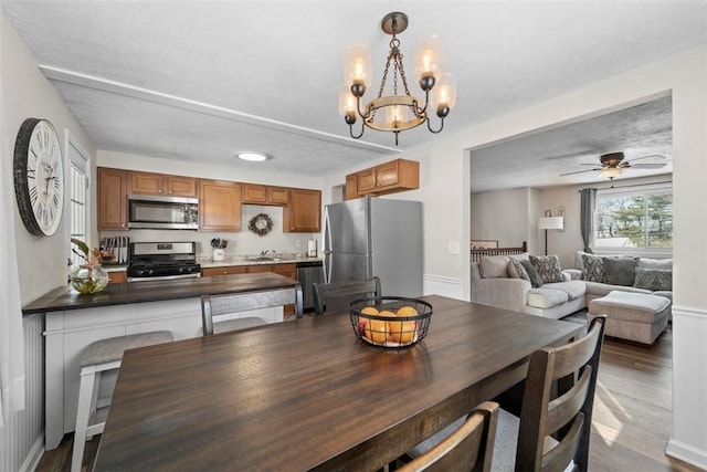 dining room featuring wood-type flooring, a notable chandelier, sink, and a textured ceiling