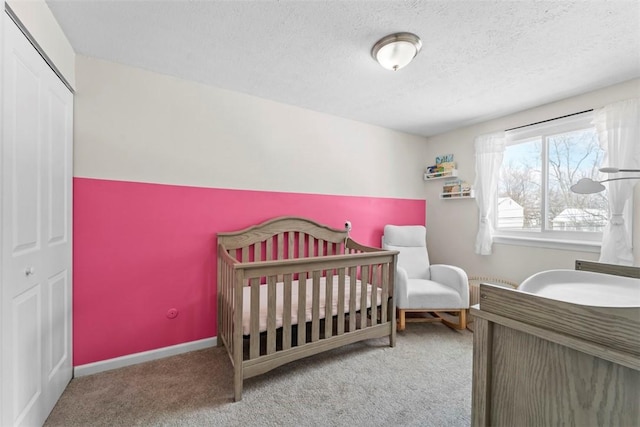 carpeted bedroom with a textured ceiling, a closet, and a crib