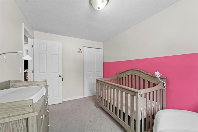 bedroom with carpet floors, a closet, a nursery area, and lofted ceiling