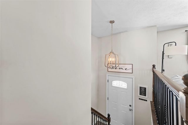 foyer with a textured ceiling and a chandelier