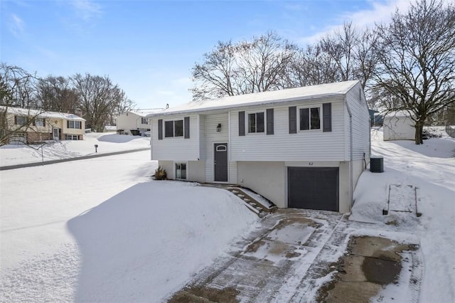 bi-level home featuring central air condition unit and a garage